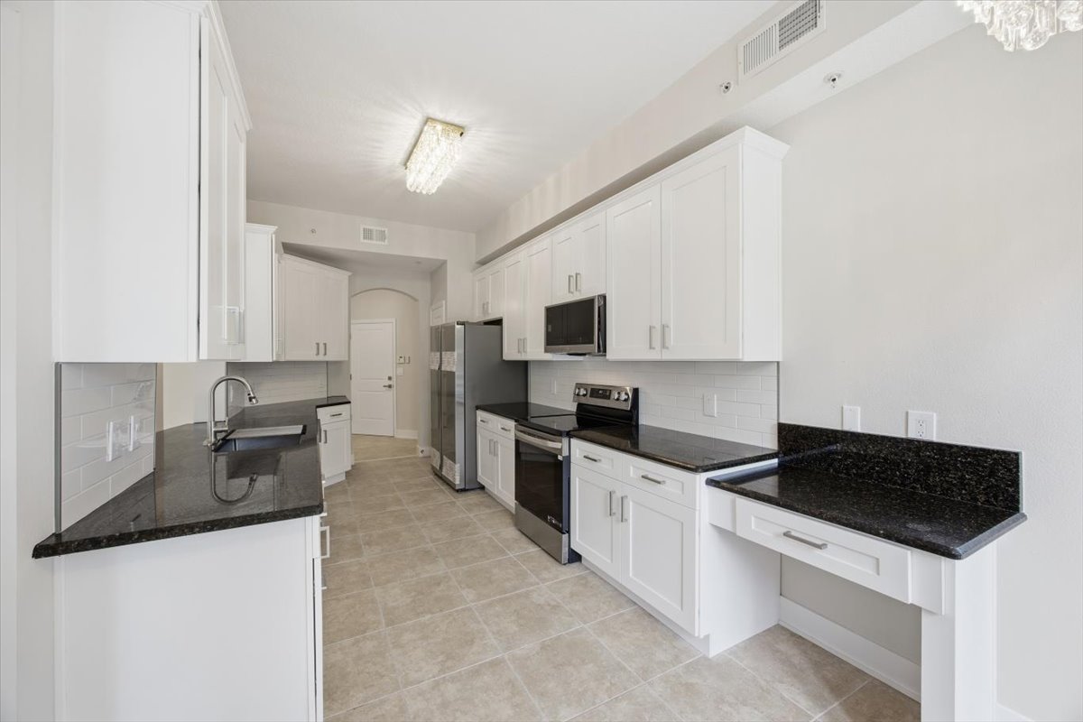 Kitchen view toward entry with stainless appliances and granite island